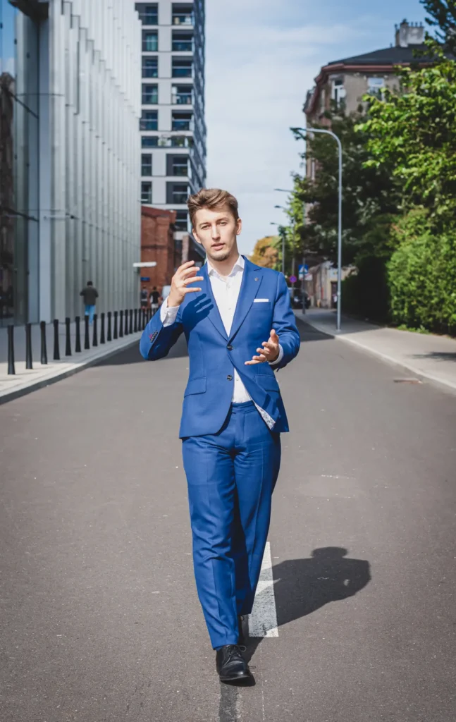 Bartosz Orzewski idzie środkiem ulicy w otoczeniu biurowców i zieleni łumacząc przykład Air Asia