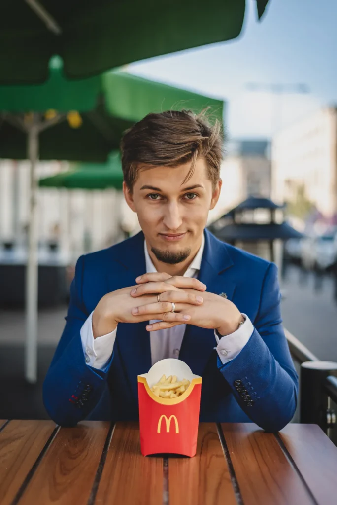 Bartosz Orzewski siedzi przy stoliku na którym stoją frytki z McDonald's